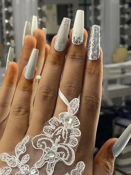 An elegant and intricate set for a white wedding theme. It features long, square-shaped nails with white 3D floral details, silver glitter, and delicate crystal accents.