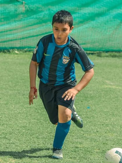A young player dribbles with determination, his eyes fixed on the goal.