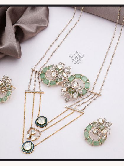 This elegant set includes a multi-strand necklace, ring, and earrings with light green stones and polki diamonds. The design is a sophisticated blend of traditional aesthetics and modern wearability.