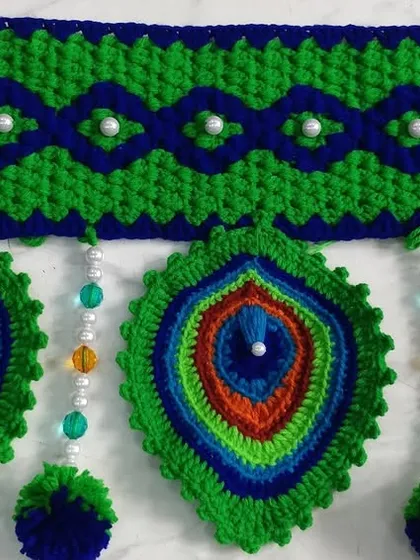 A close up of the peacock feather motif with colorful bead details, showing the intricate color work.