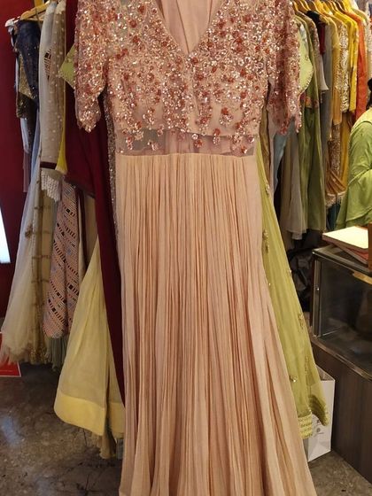 This peach gown features a beautifully embellished bodice with short sleeves and a pleated georgette skirt. It's a romantic and elegant choice for a cocktail party or an engagement ceremony.