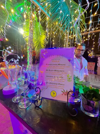 A tropical-themed bar setup for an evening party, complete with fairy lights and a custom cocktail menu. This shows how we integrate lighting and decor to create a magical ambiance.