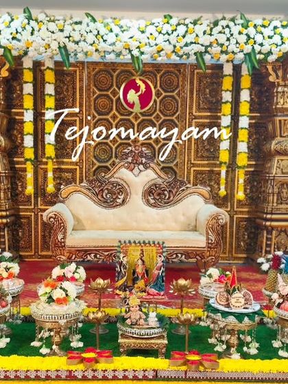 A majestic baby shower setup featuring a backdrop with intricately carved temple pillars. The traditional plate arrangement in front complements the grandeur of the stage.