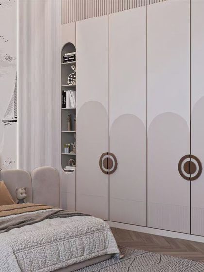 A charming nautical-themed kids' room. The wardrobe features unique circular handles and is flanked by open shelving, while the wallpaper and decor complete the seafaring adventure theme.