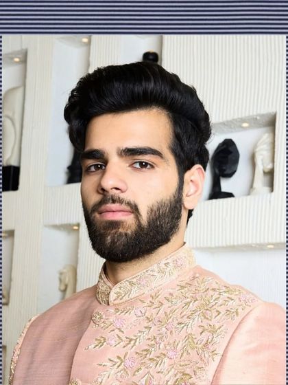 A close-up portrait in the baby pink bandhgala, highlighting the delicate threadwork on the collar and the soft texture of the raw silk fabric.