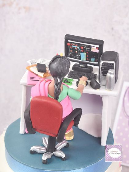A close-up of a work-from-home cake topper, showing the back of the desk setup. I included a miniature computer, keyboard, and even a tiny backpack.