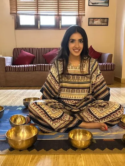 A client sits peacefully surrounded by a set of seven Tibetan singing bowls. Each bowl corresponds to one of the seven major chakras, ready for a session focused on complete energetic alignment.