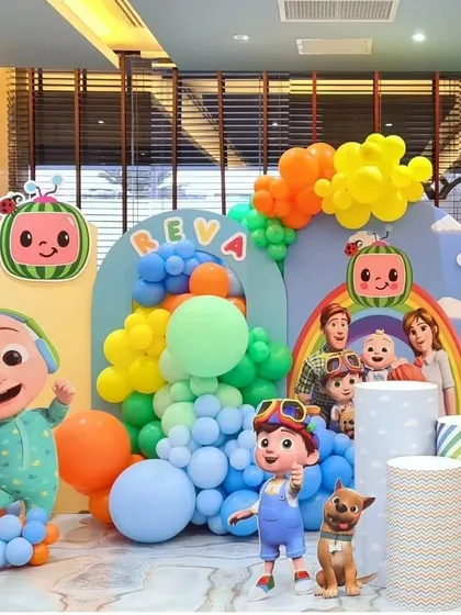 A vibrant and immersive Cocomelon themed birthday party setup. This decoration features multiple character cutouts, rainbow-colored balloon garlands, and personalized backdrops to create a fun and recognizable world for the little ones.