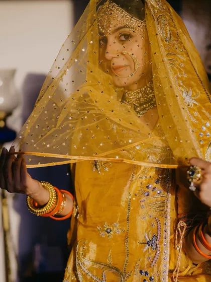 Another beautiful shot of the bride, holding her veil. The makeup is minimal, with a focus on her expressive eyes and natural skin.