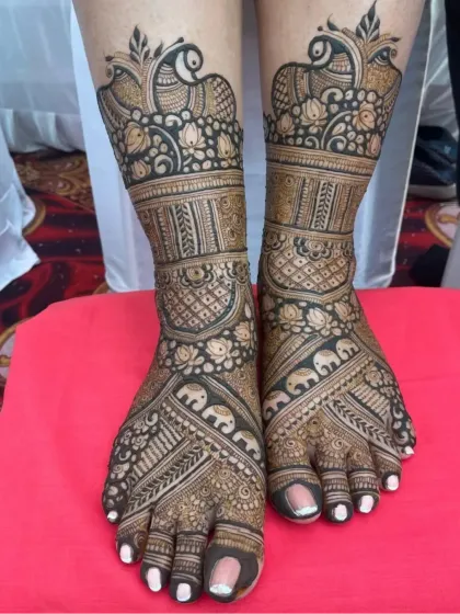 I create intricate designs for feet that are just as detailed as the hands. This piece features beautiful peacock and elephant motifs, along with fine jaali (net) patterns for a complete bridal look.