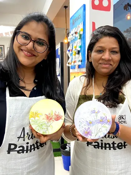 Two friends with their finished wood slice paintings. Painting on natural surfaces adds a rustic and unique charm to the artwork.