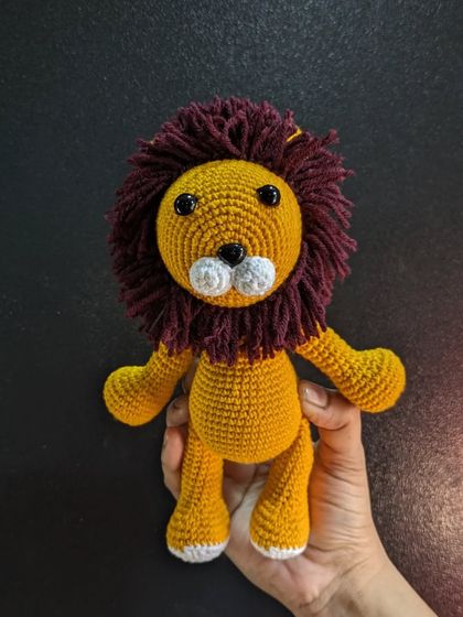 Holding the crochet lion to show his full size and fluffy mane.