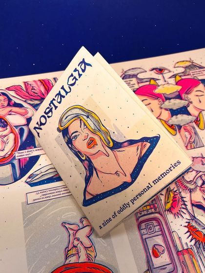 The folded zine resting on top of the full-spread artwork.