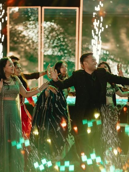 A spectacular group performance on the Sangeet stage, complete with stage lights and pyrotechnics, capturing the grandeur of the event.
