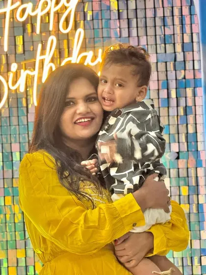 A happy mother and child posing in front of the shimmering backdrop at the Cocomelon-themed party.