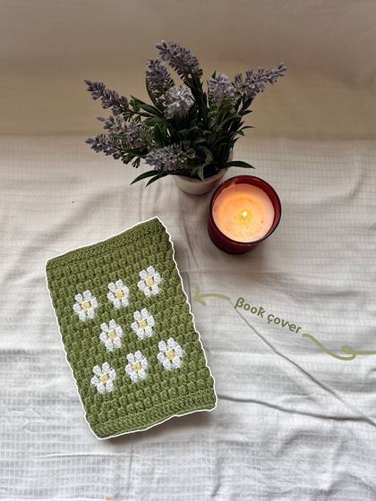 A flat-lay of the green crochet book cover with a daisy pattern, giving a clear view of the texture and design.