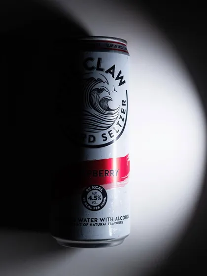 A dramatic shot of a White Claw can in a spotlight. The high-contrast lighting creates a bold and graphic image.