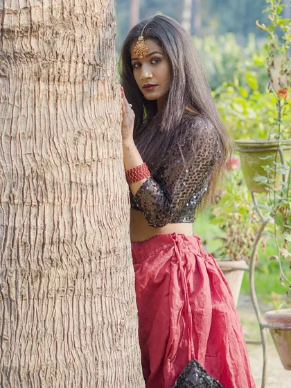 A clear and sharp portrait from an outdoor shoot, focusing on the model's pose against the tree trunk.