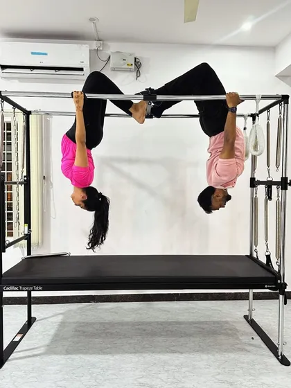 Partner work makes challenging poses more achievable. Here we are in a synchronized inverted hang on the Cadillac.