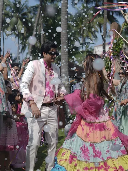 A vibrant couple entry at a tropical carnival. The bubble shower and colorful ribbons add to the festive and joyful atmosphere as they dance their way into the party.