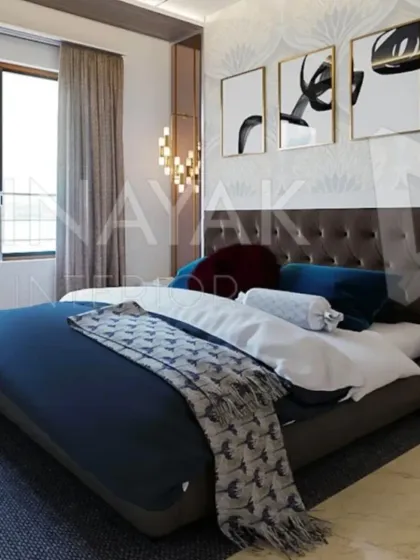 Natural light from the large window illuminates this contemporary bedroom. The abstract art triptych adds a personal touch, while the combination of a dark tufted headboard and deep blue bedding creates a sophisticated and restful color scheme.