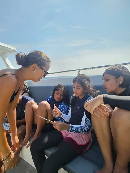 An instructor goes over the dive plan with our youth divers on the boat, pointing out the marine life they can expect to see on their fish identification slate.