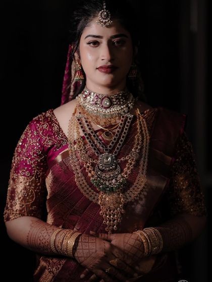 This bride's deep maroon saree for her reception is the definition of elegance. The draping style is sophisticated, with a focus on a clean pallu and perfectly falling pleats.
