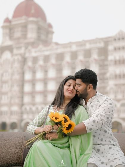 A romantic embrace with the iconic Taj Mahal Palace Hotel in the background. The sunflowers add a bright, cheerful touch to the scene.