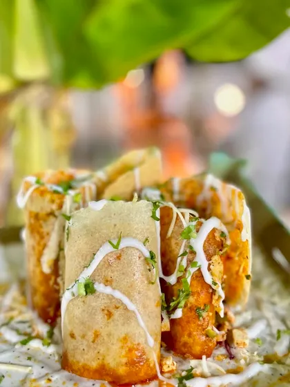My Jini Dosa is a Mumbai street food classic that I love to serve at events. The crispy dosa is filled with a mix of vegetables and sauces, rolled, cut, and topped with cheese and a creamy drizzle.