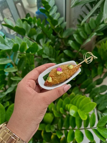 Bhetki Fish Fry, a classic Bengali appetizer, served on a skewer for easy handling at a festive gathering.