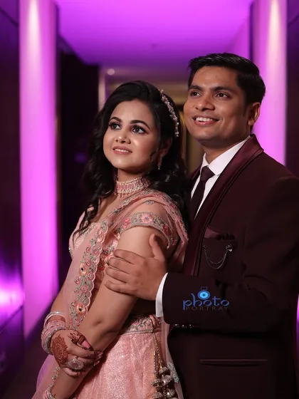 A happy and classic posed shot of the couple during their engagement. The ambient lighting of the corridor adds a warm and celebratory feel to the photograph.
