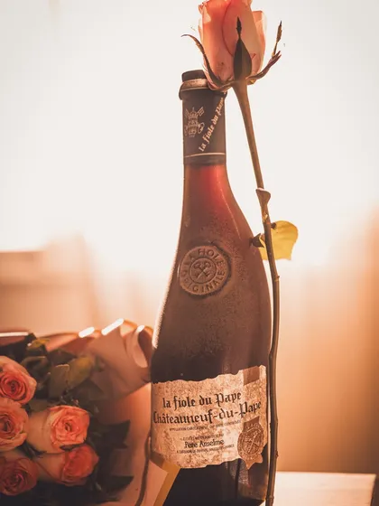 A vintage-inspired shot of a wine bottle with a single rose, using warm, golden hour light to create a feeling of old-school romance.