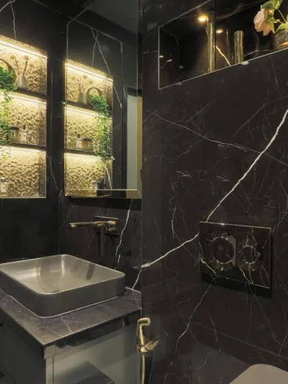 This powder room showcases the beauty of black marble. The backlit niches provide soft, ambient lighting, highlighting the decor and creating a warm, inviting glow against the dark, luxurious stone.
