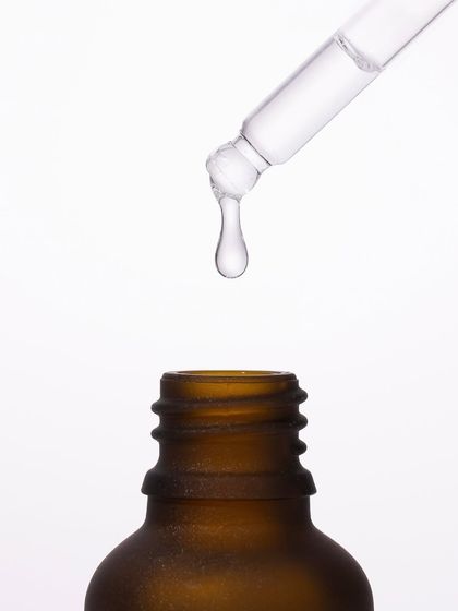 We captured the precise moment a single drop of serum falls from the dropper. This macro shot, set against a pure white background, emphasizes purity, potency, and the scientific precision behind the formula.