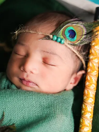 A close-up of a 6-day-old newborn as little Krishna, complete with a peacock feather headband. We can do these shoots at your home for maximum comfort.