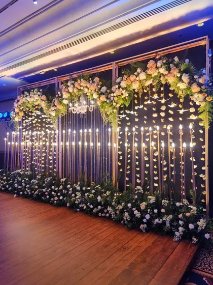 An angled view of the candle wall stage, showing the depth and dimension created by the golden frames and layers of florals. The wooden stage floor adds a touch of warmth to the sophisticated design.