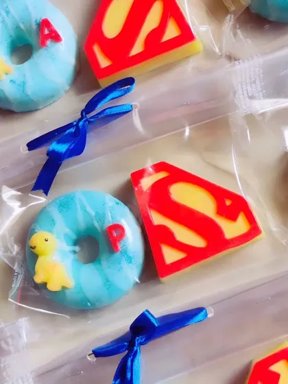 A superhero-themed return favor set, with Superman logo soaps and personalized donut soaps.