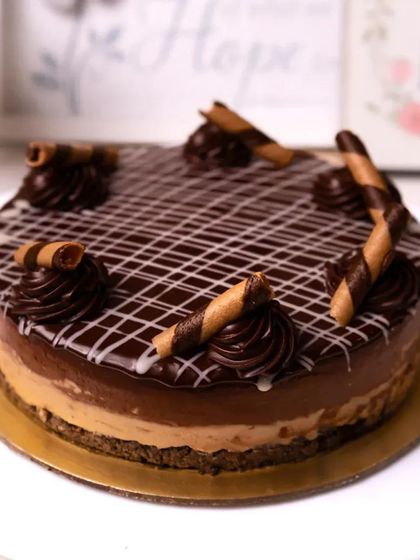 A tempting chocolate mousse cake decorated with chocolate wafer rolls and piped swirls.