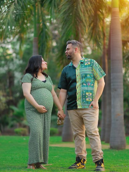 A full-length couple's portrait amidst tall palm trees. The natural setting and their connected pose create a beautiful and serene image.