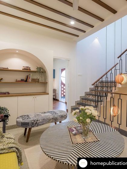 A different angle of the living area, showing the interplay of the striped coffee table, the patterned bench, and the warm wooden ceiling beams.