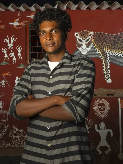 Dinesh Barap, a young Warli artist, stands before a mural that integrates the leopard into his community's cultural narrative. My work often focuses on the human element of conservation, telling the stories of people who live alongside wildlife every day.