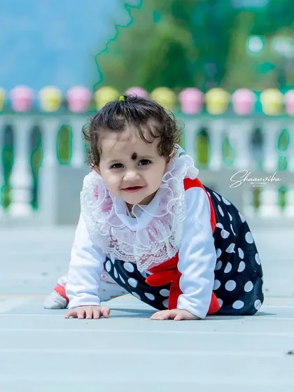 A crawling baby girl in a cute polka-dot outfit. This is a perfect example of a milestone photoshoot, capturing the precious stage of a baby learning to move around.
