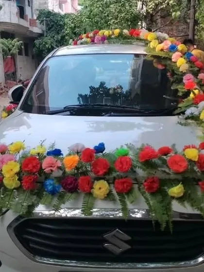 This is the front view of the car decorated with colorful artificial flowers. The arrangement covers the front grille and the roofline, ensuring the car looks festive from every angle.