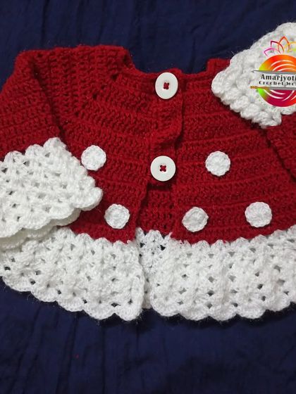 A cozy red and white polka dot crochet jacket for a baby girl. This piece is perfect for layering and adds a touch of handmade charm to any outfit, keeping your little one warm and stylish.