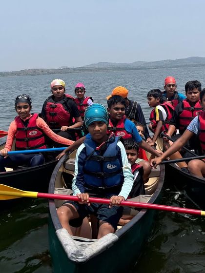 Participants in canoes work together to paddle across the lake, learning coordination and teamwork.