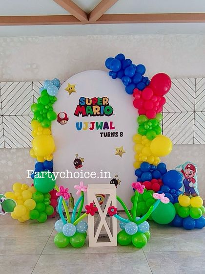 Power up the fun with a Super Mario themed birthday party. This setup includes a custom backdrop with game elements, character cutouts of Mario and Luigi, and balloon decorations in the classic red, blue, yellow, and green colors.