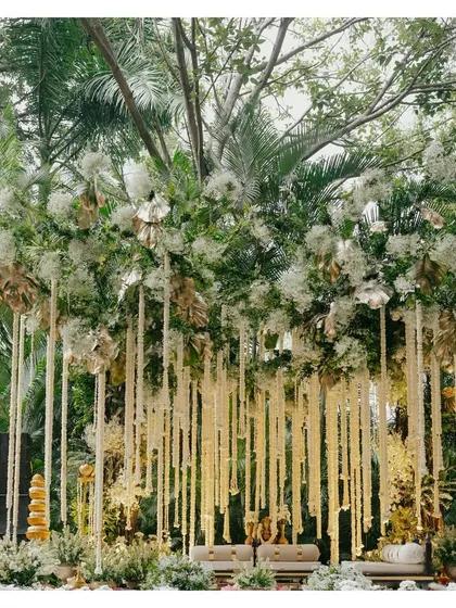 An ethereal wedding mandap designed for a modern fairytale. Draped in white florals and lush greenery, with strings of tuberoses cascading from above, this setup creates a serene and romantic ambiance for the main ceremony.