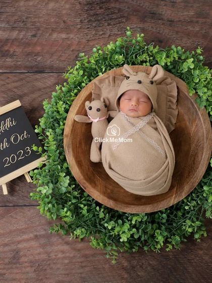 A rustic and natural setup, with the baby in a wooden bowl surrounded by a green wreath, again personalized with her name and birth date.