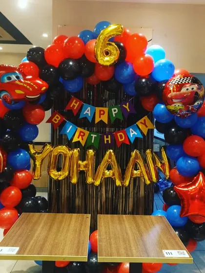 The main photo backdrop for the racing cars party, featuring a balloon arch and the birthday boy's name in foil letters.