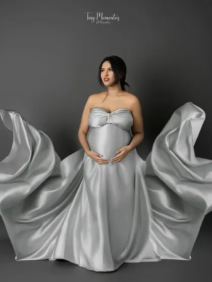 A powerful, forward-facing pose where the silver gown creates a dramatic, wing-like effect, symbolizing the strength of motherhood.